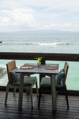 Elegant Seaside Dining Setup Featuring Wooden Tables and Ocean Views in a Tranquil Restaurant Atmosphere.