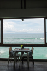Elegant Seaside Dining Setup Featuring Wooden Tables and Ocean Views in a Tranquil Restaurant Atmosphere.