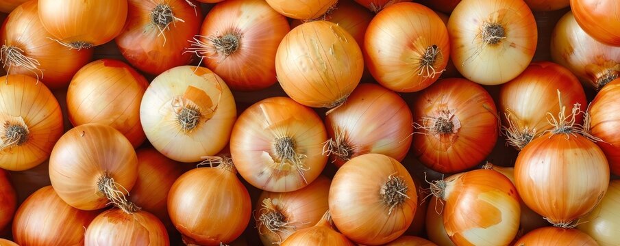   A pile of onions stacked on top of one another, atop a larger pile