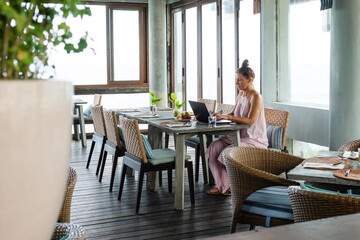 Freelancer Woman Working Remotely on a Laptop in a Modern, Serene Workspace with Natural Light and Comfortable Seating.