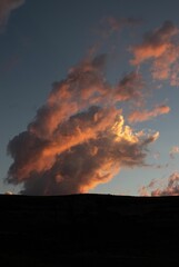 Vertical shot of pink sunset clouds with a land silhouette