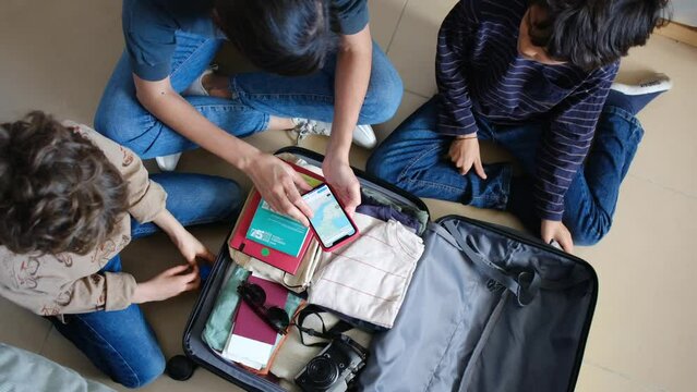  Woman preparing suitcase with 2 sons trip . Checking suitcase ,mobile application, flights,  route, destination, documentation, summer.