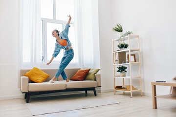 Joyful Woman Jumping with Music, Singing and Dancing in a Playful Indoor Home Concept