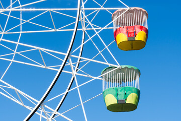 Background of two colored cabins of a ferris wheel rotating in a blue sky