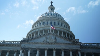 The US Capitol dome with flag at half mast, seat of government in Washington, DC on a beautiful sunny day with clear blue sky.