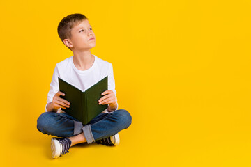 Full length photo of thoughtful dreamy kid dressed white shirt reading fairytale looking empty...