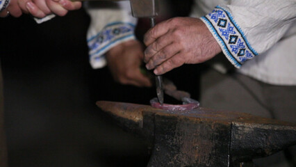 Hands of a blacksmith working on a horseshoe on the anvil
