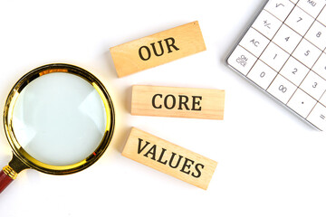 Concept words OUR CORE VALUES symbol on wooden blocks on a white background next to a calculator...