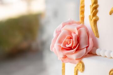 fondant rose on an elegant wedding cake with gold accents - obrazy, fototapety, plakaty