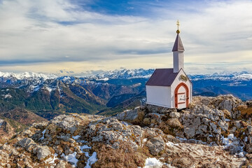 Eine einsame Miniatur Kapelle auf dem Hochgern Gipfel in den Chiemgauer Bergen umgeben von Felsen und Schnee in Bayern Deutschland