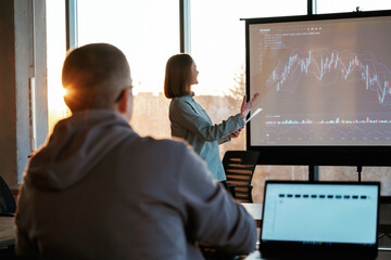 Beautiful sun beam. Female business trainer is against projector with business data, teaching the...