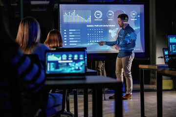 Helping to grow the company. Male business trainer is against projector with data, teaching people