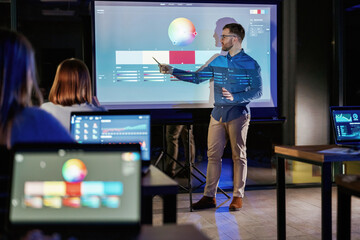 Design tools. Male business trainer is against projector with data, teaching people