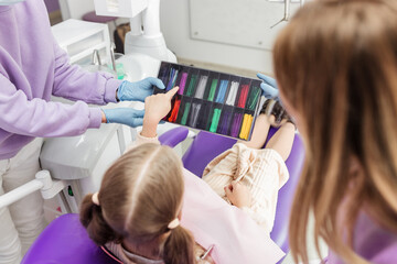 schoolgirl girl chooses the color of rubber bands for braces, pediatric dentistry - obrazy, fototapety, plakaty