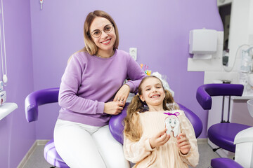 Smiling dentist and patient looking at camera portrait. Well-equipped dental clinic office....