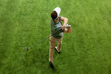 High overhead angle view of skilled golfer in casual attire hitting golf ball on fairway green grass. Concept of professional sport, luxury games, active lifestyle, action. Ad