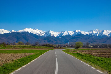 Beautiful landscape with a road leading to the Fagaras mountains with snow on the peaks