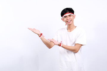 Happy asian young boy with red white ribbon celebrating Indonesia independence day while presenting...