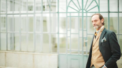 Senior businessman with confident stance near glass structure.