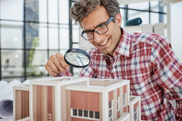 the guy looks at the layout of the house through a magnifying glass