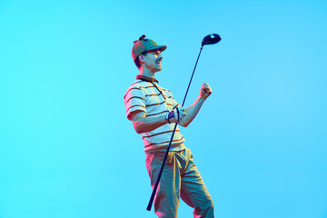 Overjoyed golf player in retro clothes and cap raising hands after perfect goal in neon light...