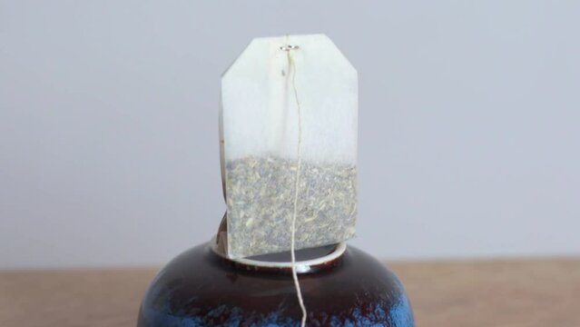 One tea bag on a ceramic stand. A blank yellow label without logos is displayed on a white background.