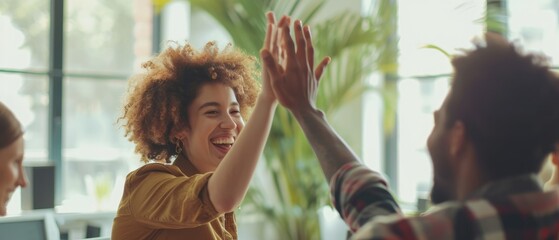 Happy young woman worker giving male colleague high five celebrating good team work results, financial success in professional teamwork at diverse coworkers group office meeting