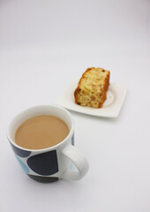 An image of a very tasty pie on a white plate and a cup of coffee with milk on a white background.