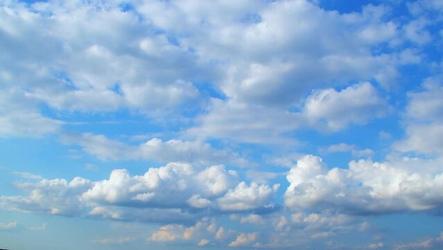 Beautiful cumulus clouds slowly move across the sky. Calm landscape with white clouds and blue, summer sky.