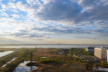Picturesque scenery with a field and a lake under clouds at sunset