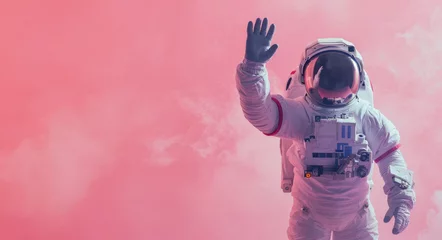 Foto auf Alu-Dibond An astronaut waves capturing a human connection in a solitary smoky, pink environment, suggesting camaraderie © Fxquadro