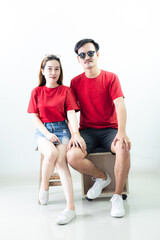 Obraz premium Young Asian couple isolated on white background,Young attractive Asian couple wearing red t shirt and white shorts standing together, woman holding bouquet of flower against white background. Concept 