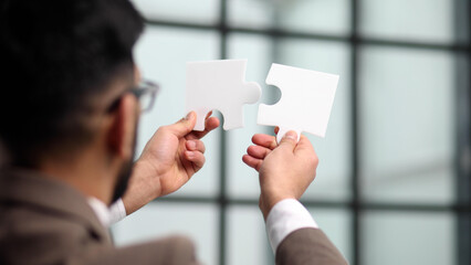 Businessman trying to connect puzzle pieces closeup