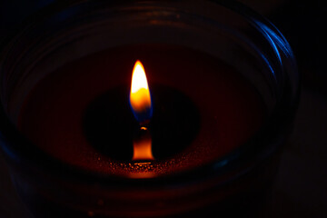 Beautiful burning candle with the flame reflection on the melted wax Closeup. Oil lantern. Blue...