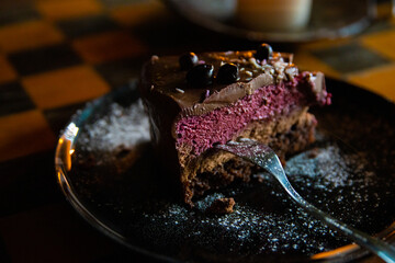 Piece of delicious homemade chocolate cake with blackberries and raspberries dusted with sugar...