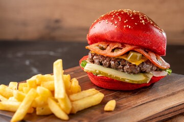 Burger with red bun on wooden board with drink