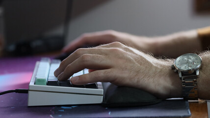 A man wearing a watch and typing on a keyboard while working from home