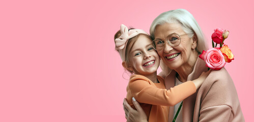 Smiling daughter hugs Grandmother bouquet of flowers, pink background, copy space, happy mother's day greeting