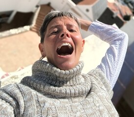Close-up of a woman, with half-closed, frightened eyes and open mouth, with one arm raised and...
