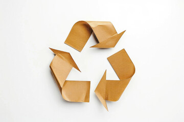 The image depicts a classic recycling sign made of cut-out recycled cardboard, illustrating a message of sustainability