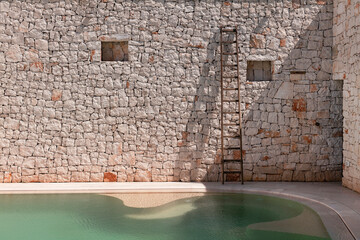 Muro a secco con piscina e scala di legno