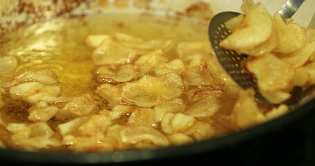 Frying traditional potatoes crisps on large frying pan