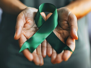 Hands holding a green ribbon for mental health awareness and support