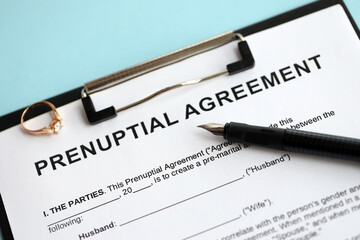 Prenuptial agreement and wedding ring on table. Premarital paperwork process close up