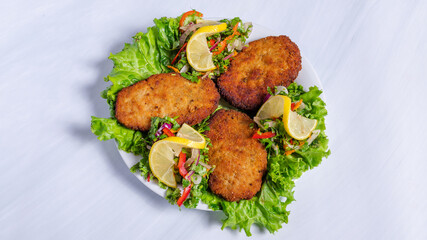 Fried cutlets on lettuce leaf with vegetables on plate top view