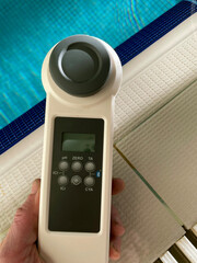 Digital water tester provides accurate readings of crystal clear water with beige tiled floor,...