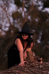 A witch dressed in black dress in the forest	