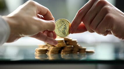 Two people are holding a gold coin and a pile of gold coins