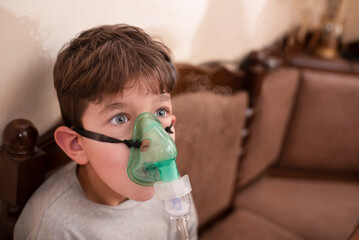 A young boy was walking in cold weather and fell ill with pneumonia and is now being treated at home, he inhales medicine through inhaler, inhalation warms the throat and lungs