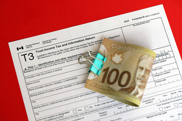 Canadian T3 tax form Trust income tax and information return lies on table with canadian money bills close up. Taxation and annual accountant paperwork in Canada